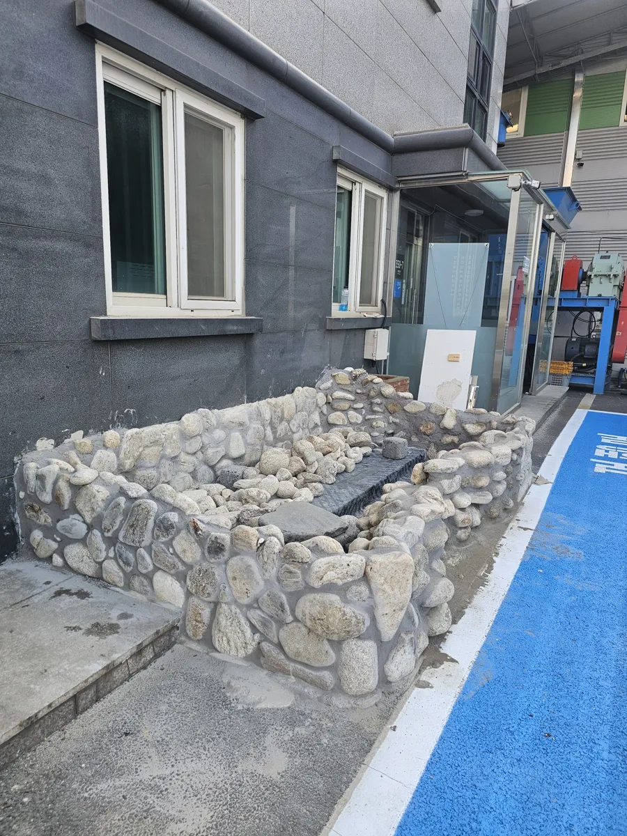 돌쌓기로 완성된 건물 옆 소형 연못 전경